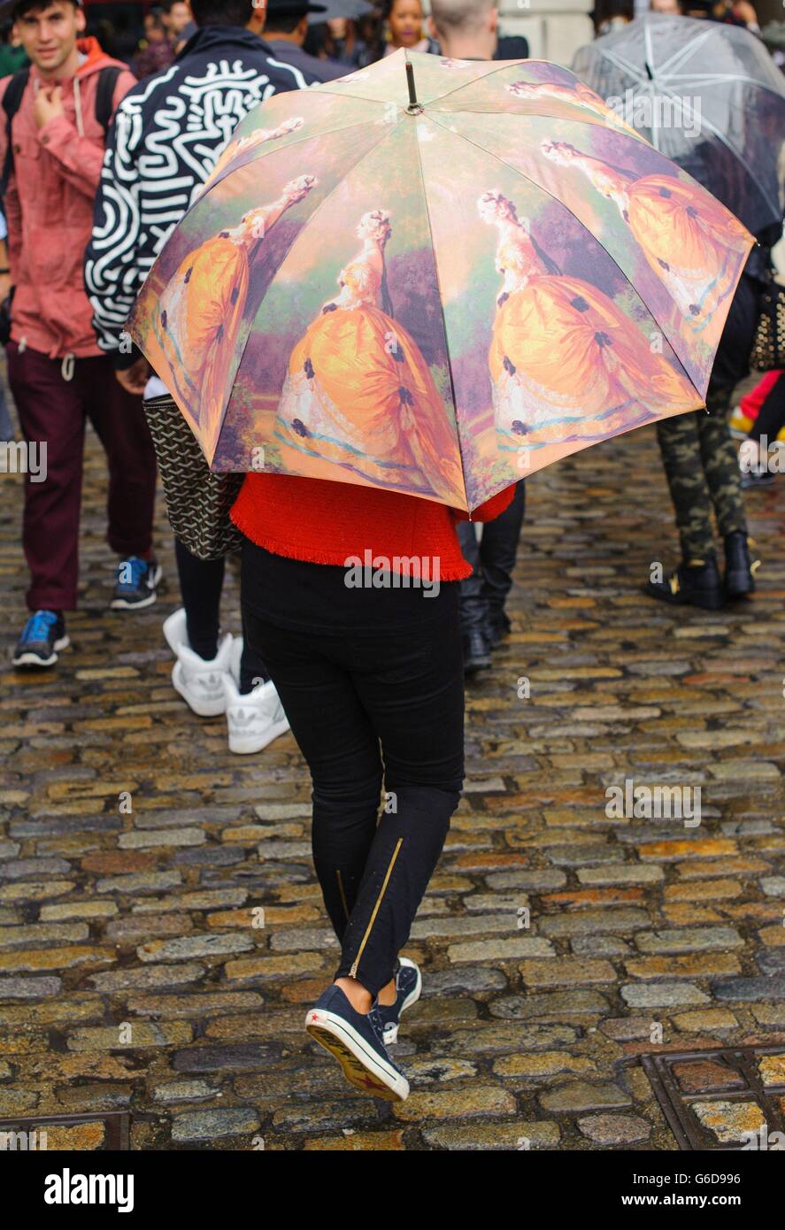 Arrivals - London Fashion Week 2013. An attendee shelters from the rain at Somerset House, central London, during London Fashion Week 2013. Stock Photo