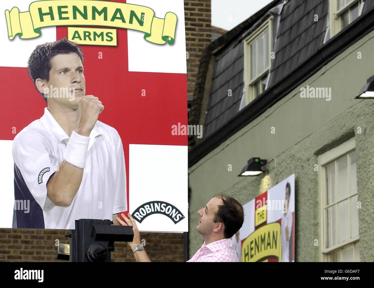 Adam Jennings, the licencee of The Sun Inn in Barnes, south west London, adjusts his new signboard as the pub prepares for Tim Henman's third round tie at Wimbledon. The pub, which serves as the England Number One's 'local', is to be dubbed 'The Henman Arms' for the day. Stock Photo