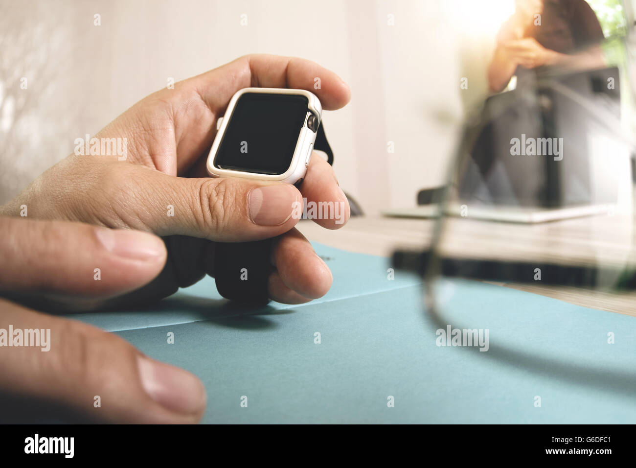 business presentation meeting on office table with smart watch and laptop computer and graph business diagram and three colleagues discussing data in the background Stock Photo