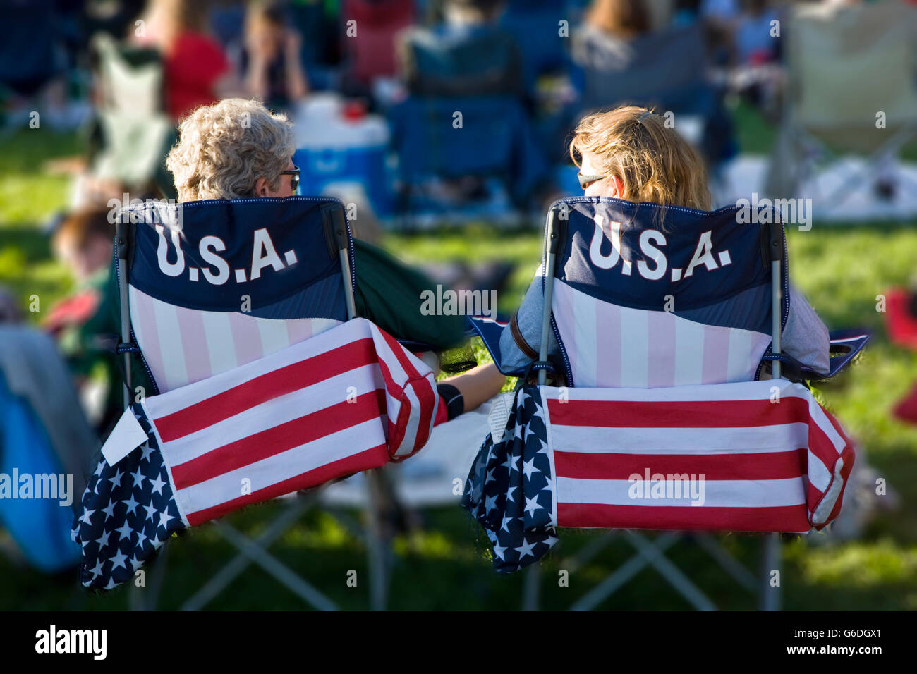 Woman in flag decorated chairs listening to a musical band play music in Riverside Park, Salida, Colorado, on the Fourth of July Stock Photo