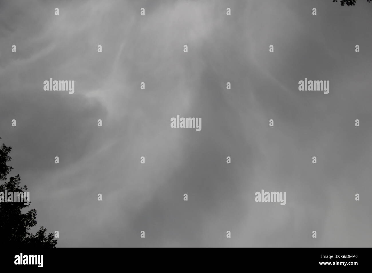 Dark storm clouds gather in the sky above trees before a powerful ...