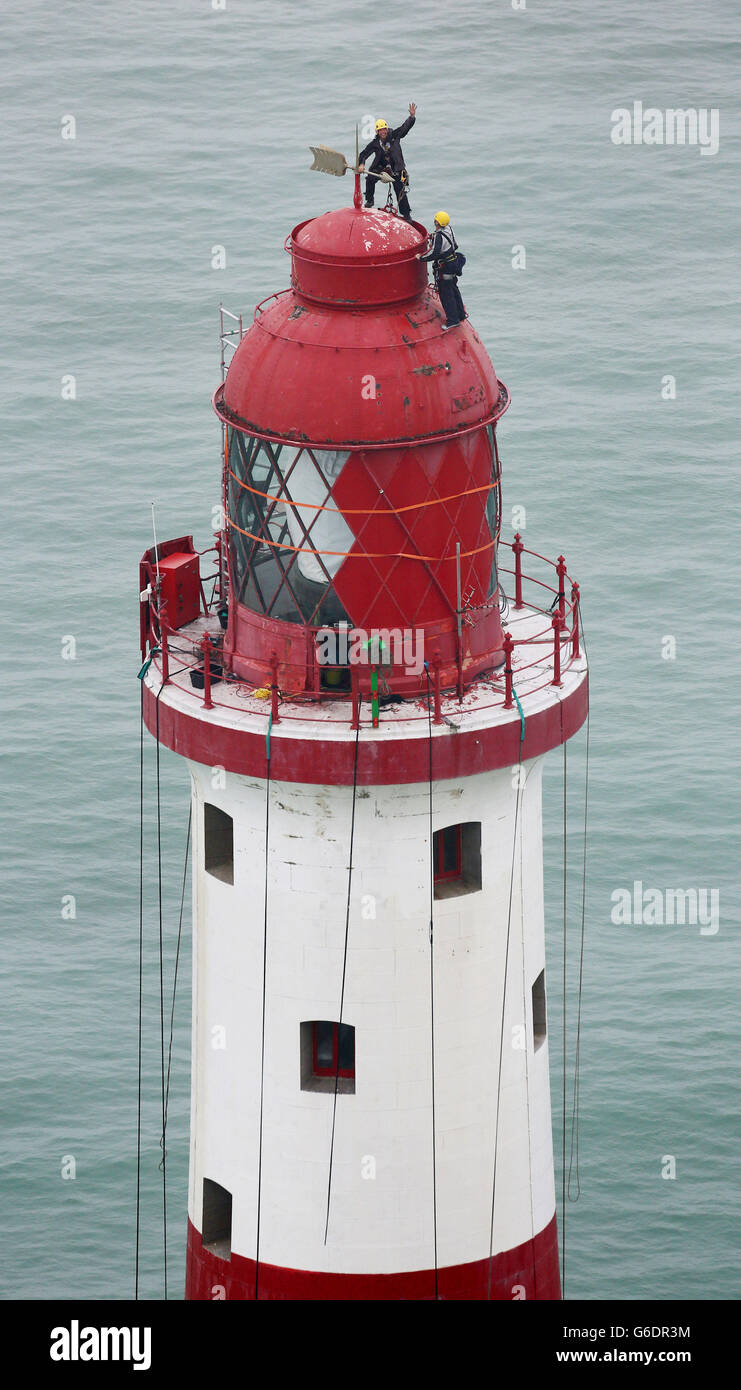 Engineers balance at the top of Beachy Head Lighthouse near Eastbourne, Sussex, as the process of repainting the structure following a successful fund raising campaign to save the stripes begins. Stock Photo