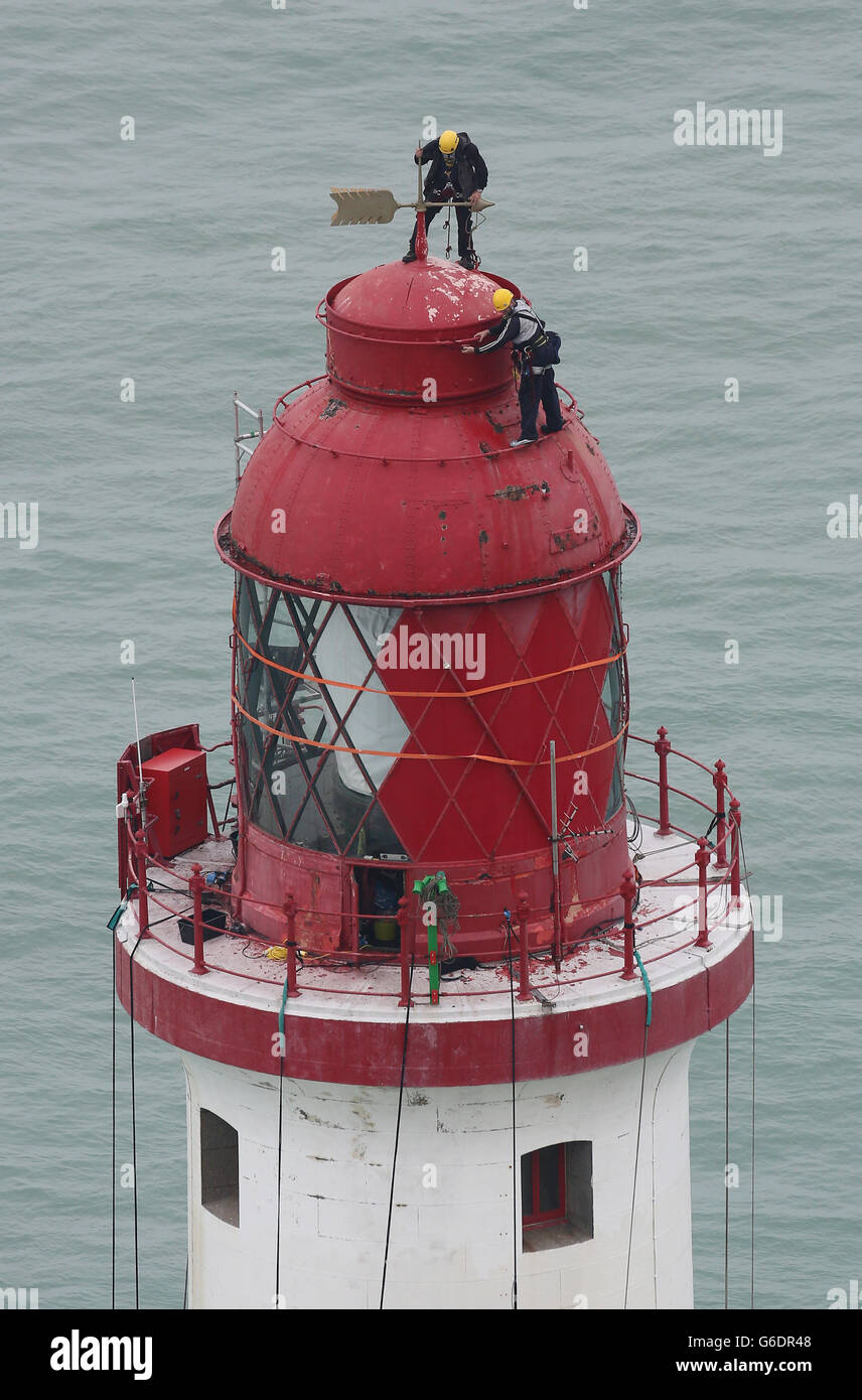 Engineers balance at the top of Beachy Head Lighthouse near Eastbourne, Sussex, as the process of repainting the structure following a successful fund raising campaign to save the stripes begins. Stock Photo