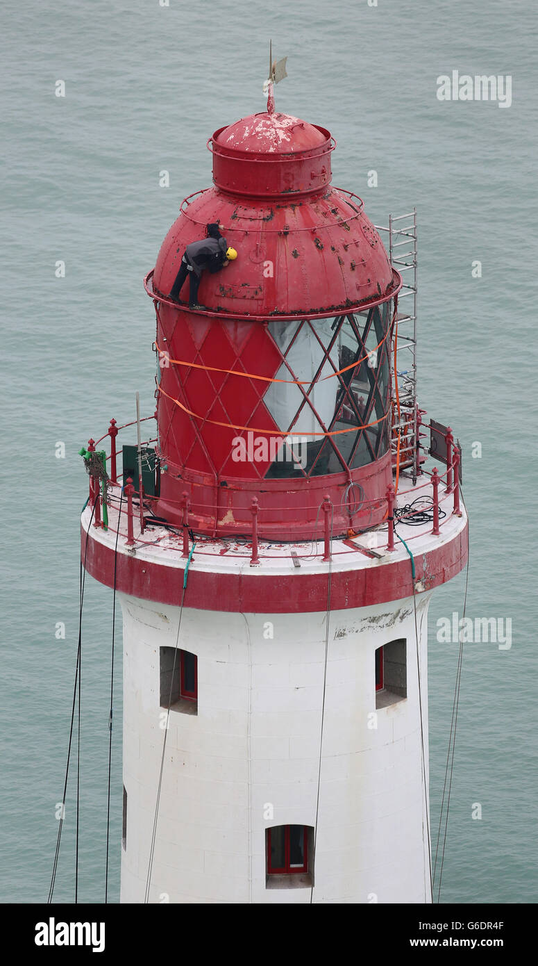 Engineers work at the top of Beachy Head Lighthouse near Eastbourne, Sussex, as the process of repainting the structure following a successful fund raising campaign to save the stripes begins. Stock Photo