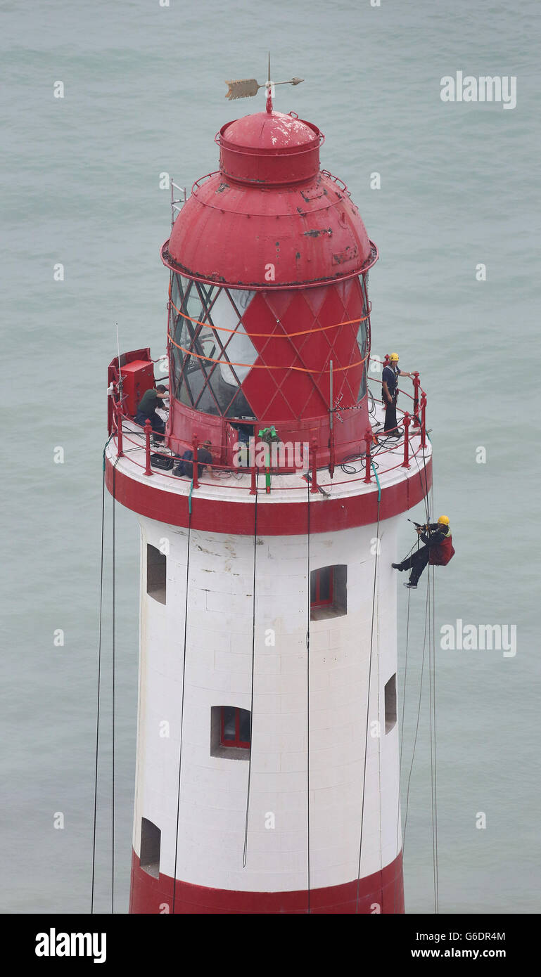 Engineers work at the top of Beachy Head Lighthouse near Eastbourne, Sussex, as the process of repainting the structure following a successful fund raising campaign to save the stripes begins. Stock Photo