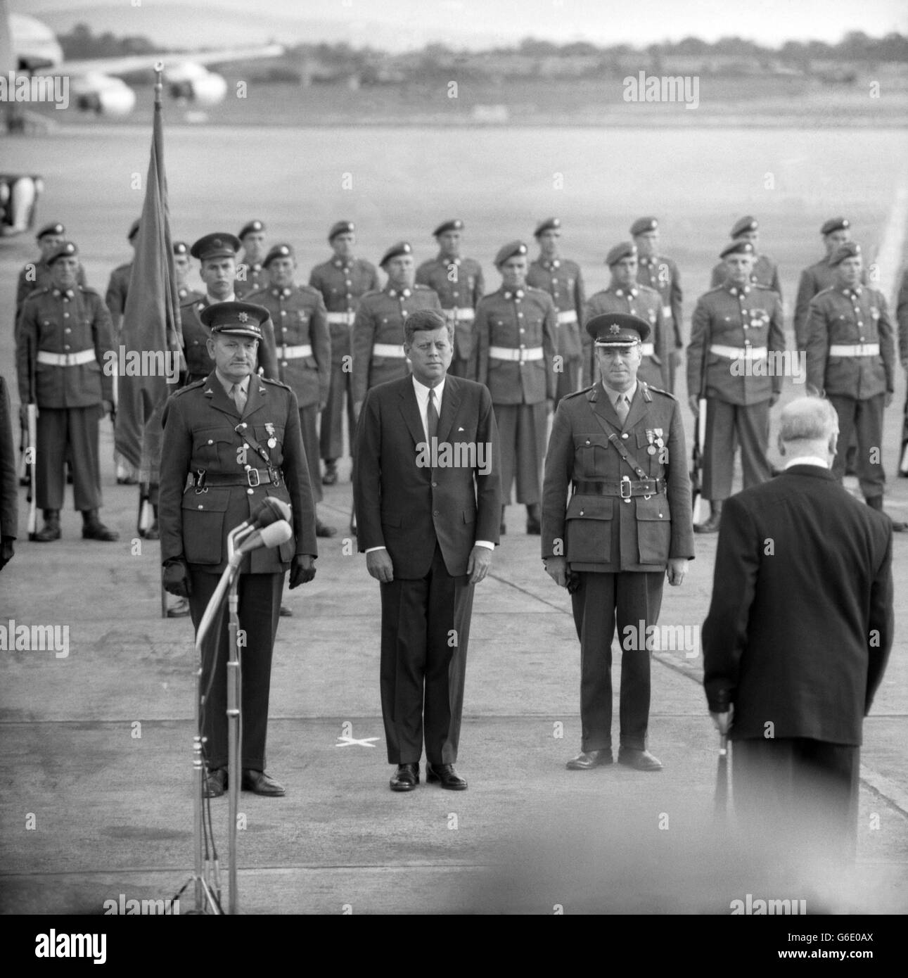 President JOHN. F. KENNEDY stands rigidly at attention in front of the guard of honour as an Irish Army band plays the American national anthem on his arrival at Dublin Airport to begin an Irish tour lasting until Saturday. After the official welcoming ceremonies, in which Mr. Kennedy was greeted by President Eamonn de Valera of the Irish Republic, the two Presidents took their seats in an open car to drive in a motorcade the eight miles to the American Embassy in Dublin, where President Kennedy is to stay. Stock Photo