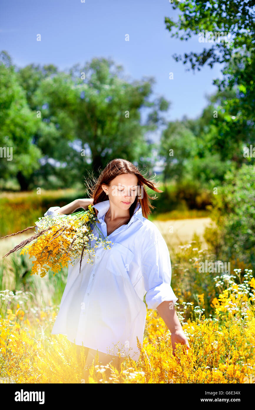 The girl holds a bouquet of wild flowers in hand. Stock Photo