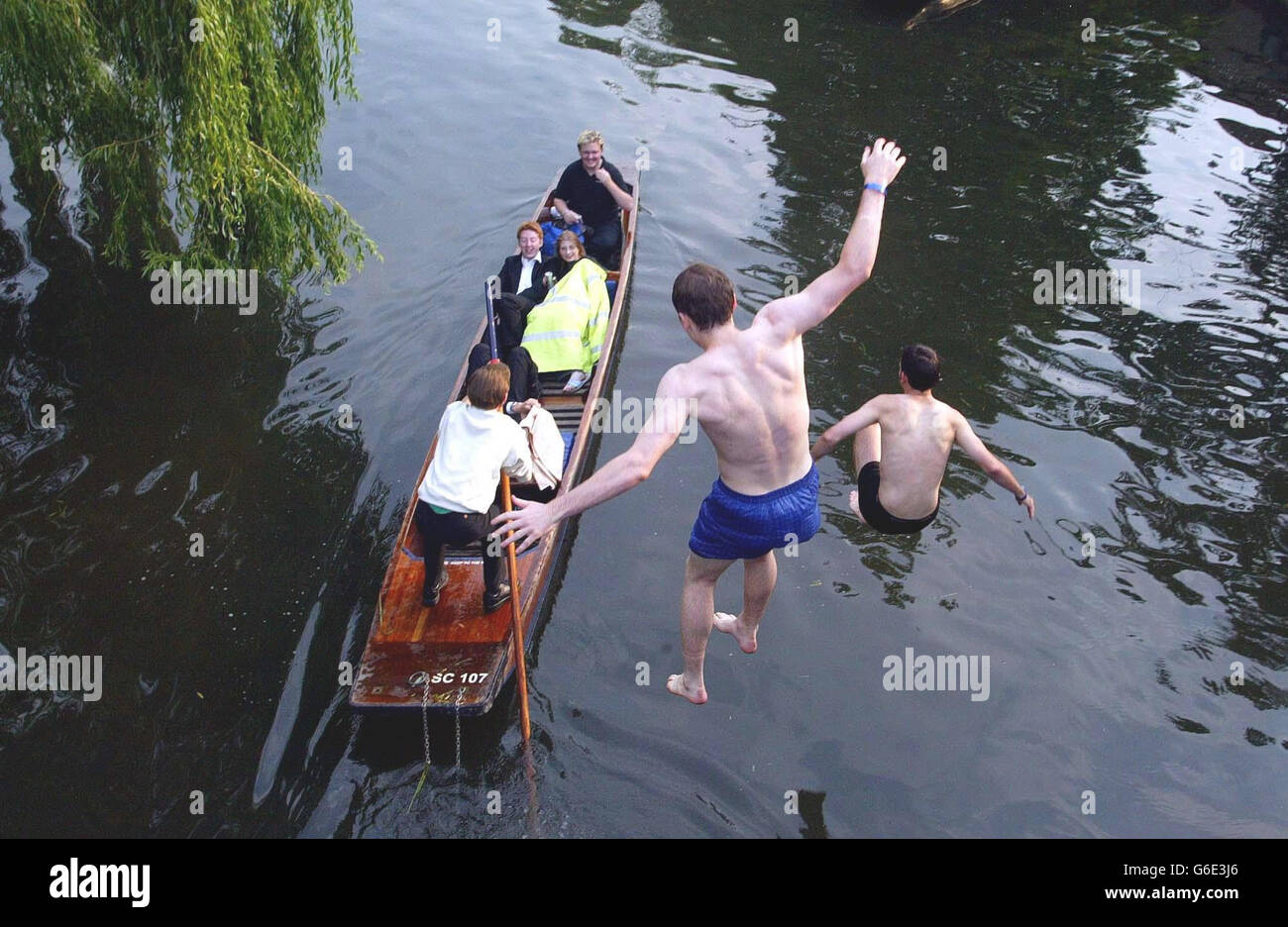 Cambridge students Sam Prentice, 21, (blue shorts), from Cambridge, Massachusetts, USA and Tom Simpson, 19, from Whitley Bay, near Newcastle upon Tyne, who are both studying at Clare College, jump from a bridge over the river Cam in Cambridge, after celebrating the end of term by going to Clare May Ball. * The college balls held during May Week - a fortnight in June - are the traditional way for students to let their hair down after taking their end-of-year exams. Stock Photo