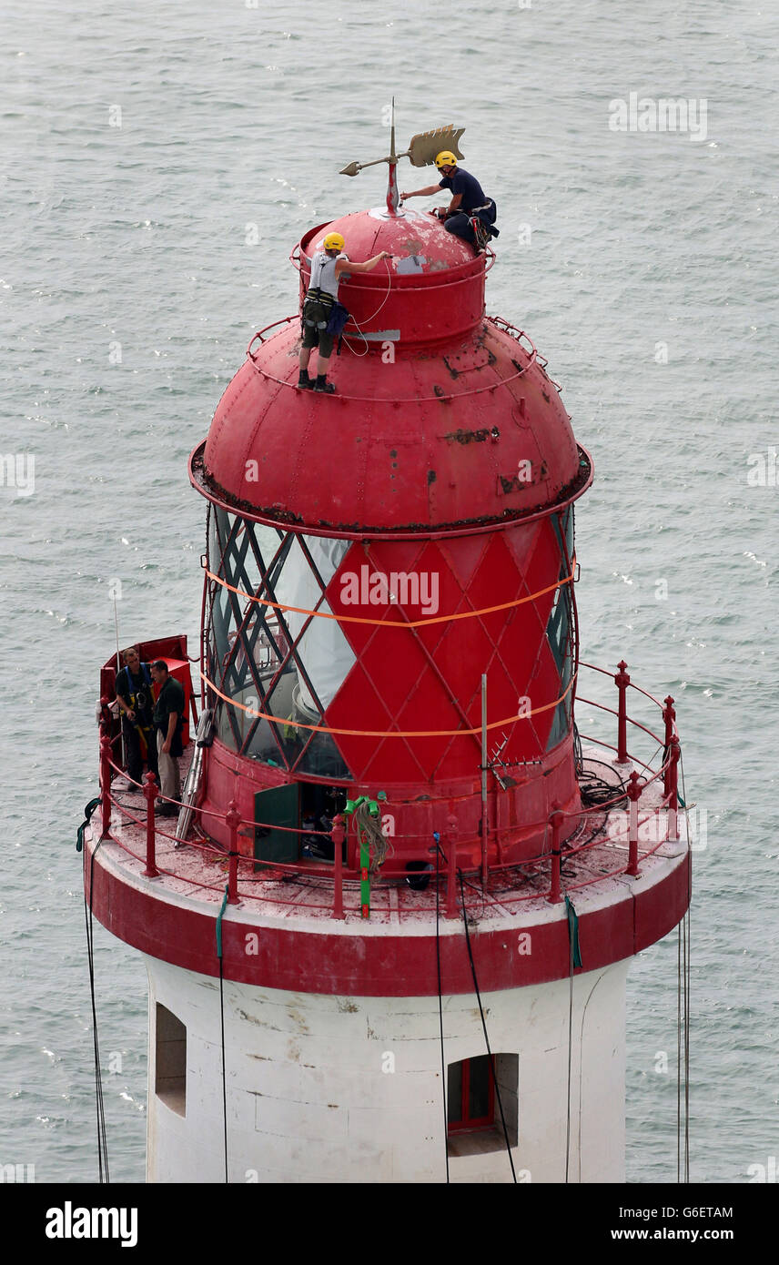 Specialist painters apply the first strokes of paint to the lantern housing at the top of Beachy Head Lighthouse near Eastbourne, Sussex, as the process of repainting the structure begins following a successful fund raising campaign to save the stripes. Stock Photo