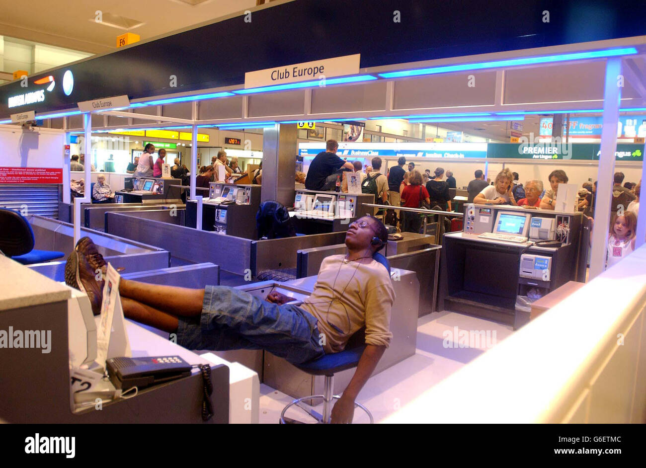 A tired traveller sleeps behind the British Airways customer help desk, at Heathrow Airport's Terminal One, London, following strike action taken by British Airway's staff . Stock Photo