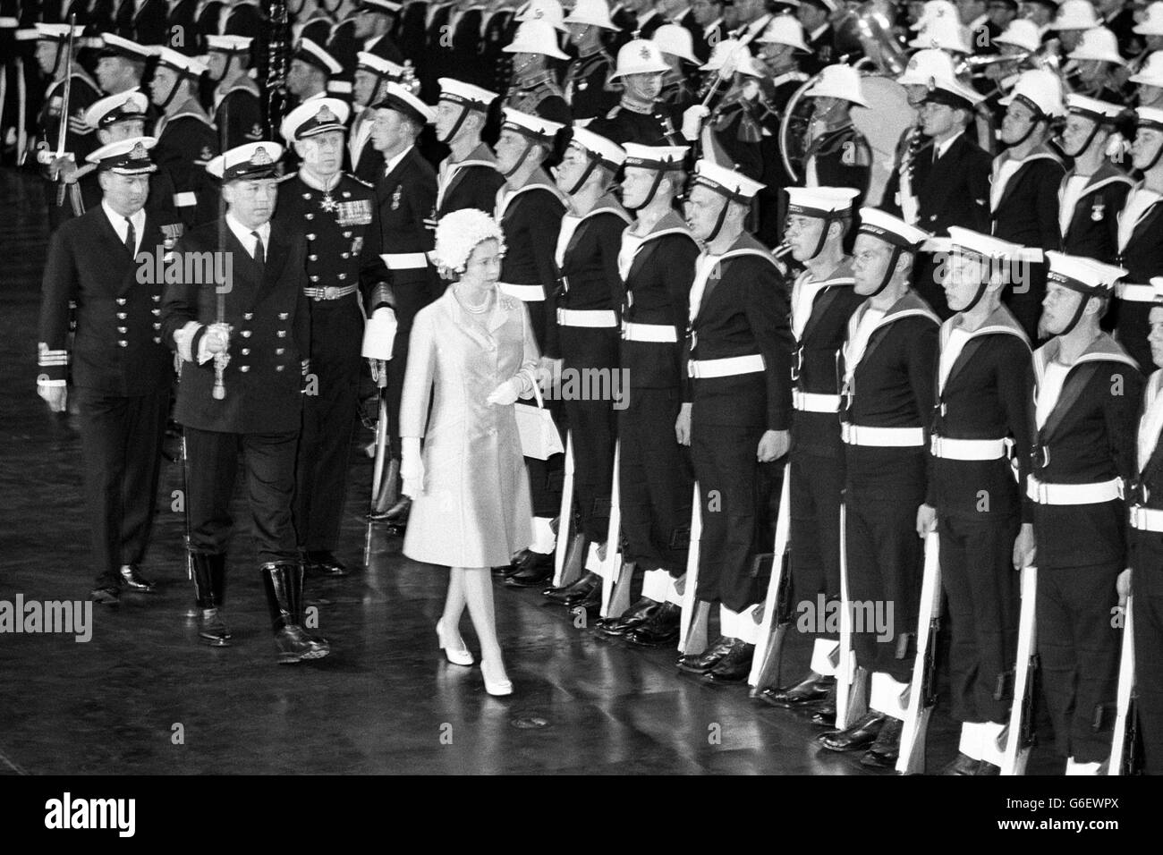 The Queen inspecting the Colour Guard in the hanger aboard aircraft carrier HMS Eagle in Torbay, Devon. She presented a new colour to the western Fleet. The ceremony was held in the hanger because of high wind. Stock Photo