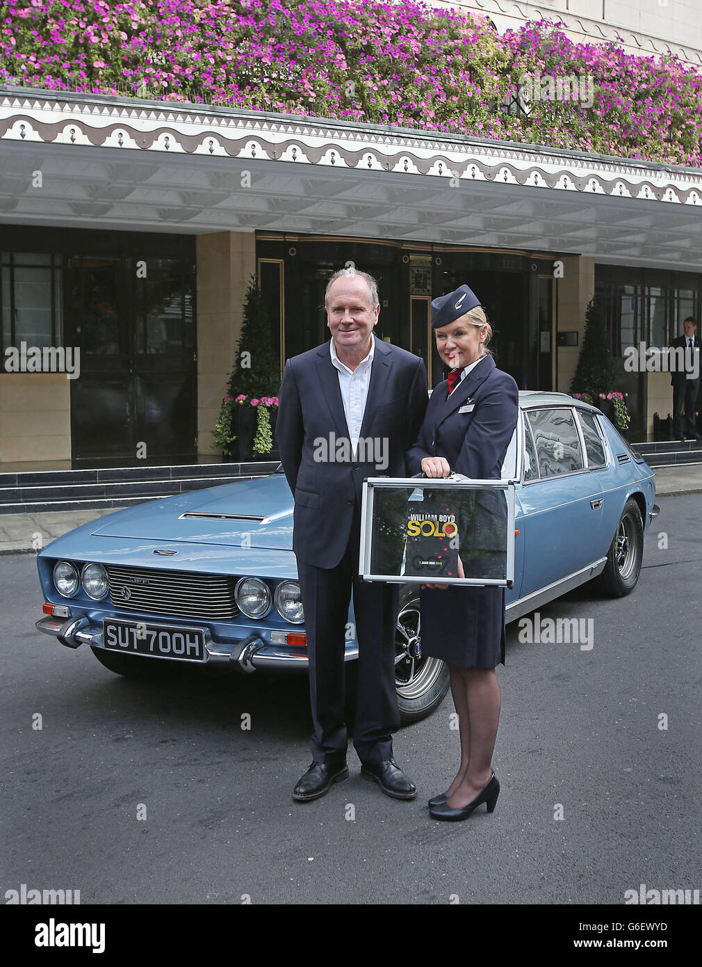 Author William Boyd holding his new James Bond novel in front of a Jenson car outside the Dorchester hotel in London with Helena Flynn, a British Airways cabin crew steward. Stock Photo