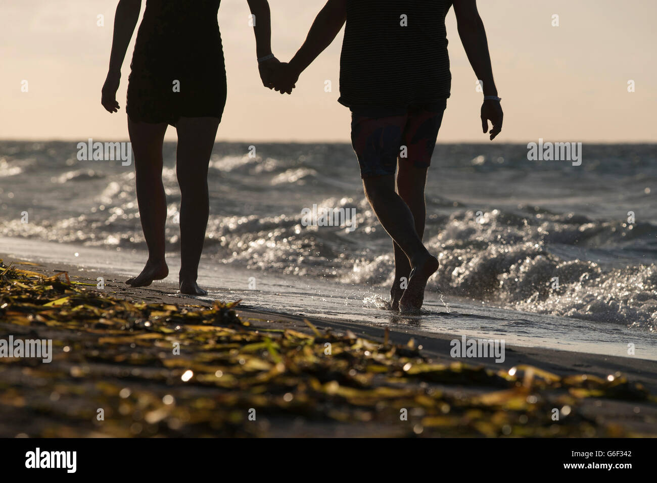 A couple walking hand in hand along on a tropical beach Stock Photo