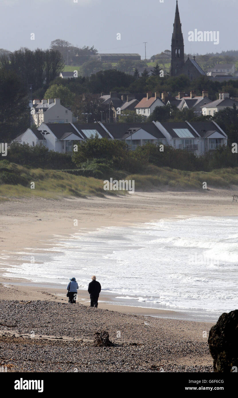 Two people walk along the beach at Ballycasle in Co Antrim, as strong winds force ferry crossings to nearby Rathlin island to be cancelled. Stock Photo