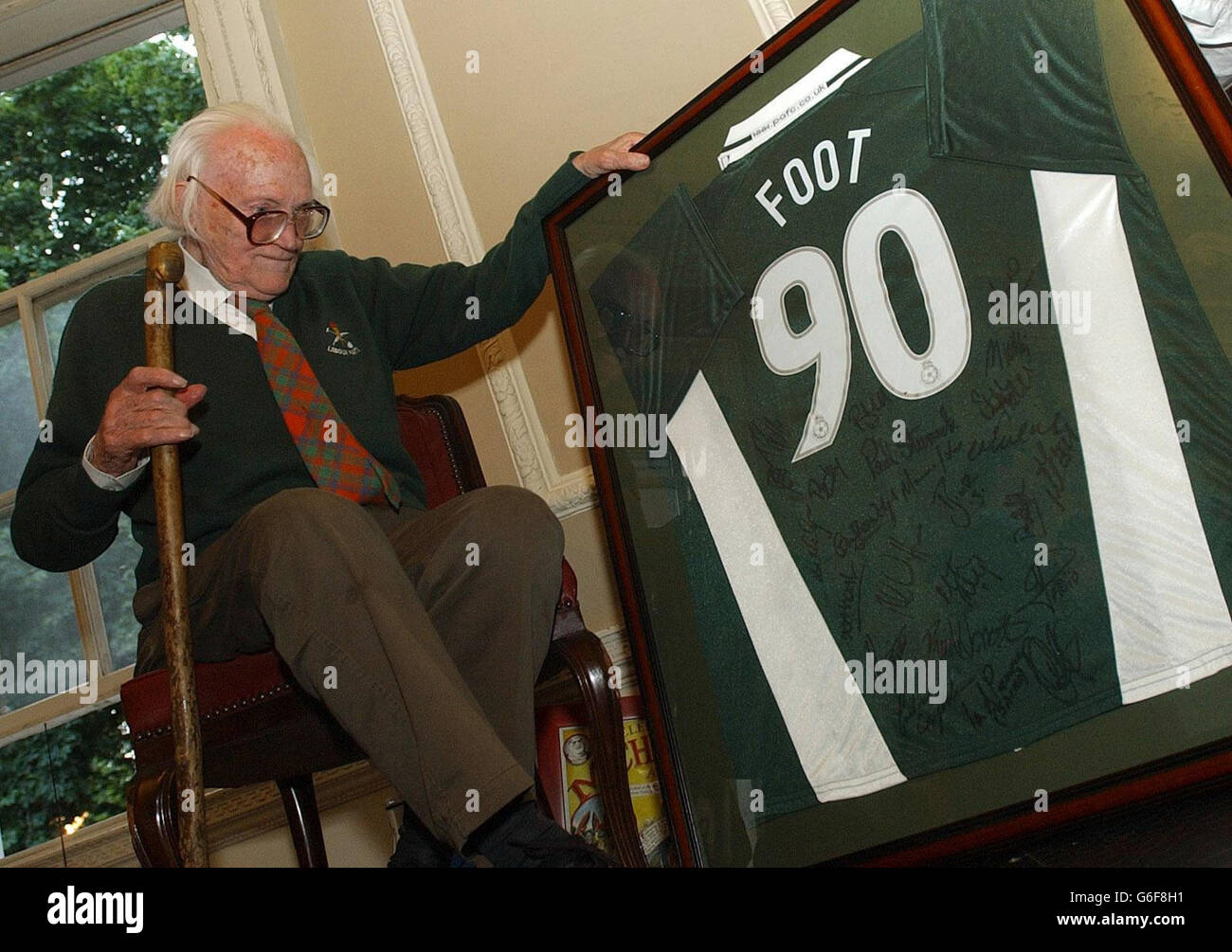 Former Labour Party leader Michael Foot looks at a football shirt given to him as a present at the Gay Hussar in Soho, London, at a party being held to mark his 90th birthday. Stock Photo