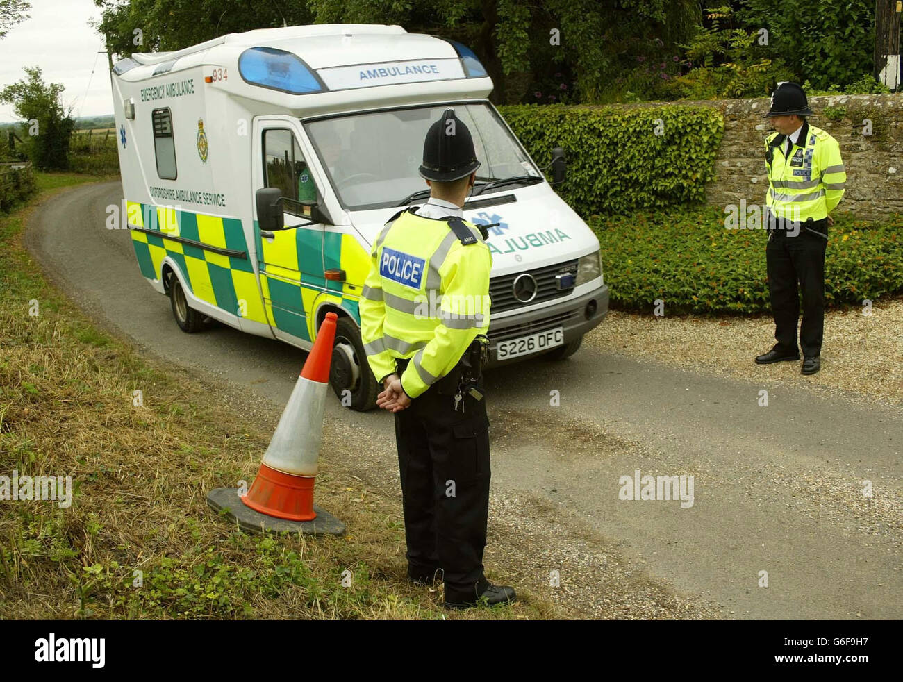 Police officers watch as an ambulance leaves Harrowdown Hill in Oxfordshire where a man's body was found. Dr David Kelly, who is thought to be the Ministry of Defence mole who briefed BBC journalist Andrew Gilligan about the build up to the Gulf War, * ... has been missing from his home nearby since yesterday. Stock Photo