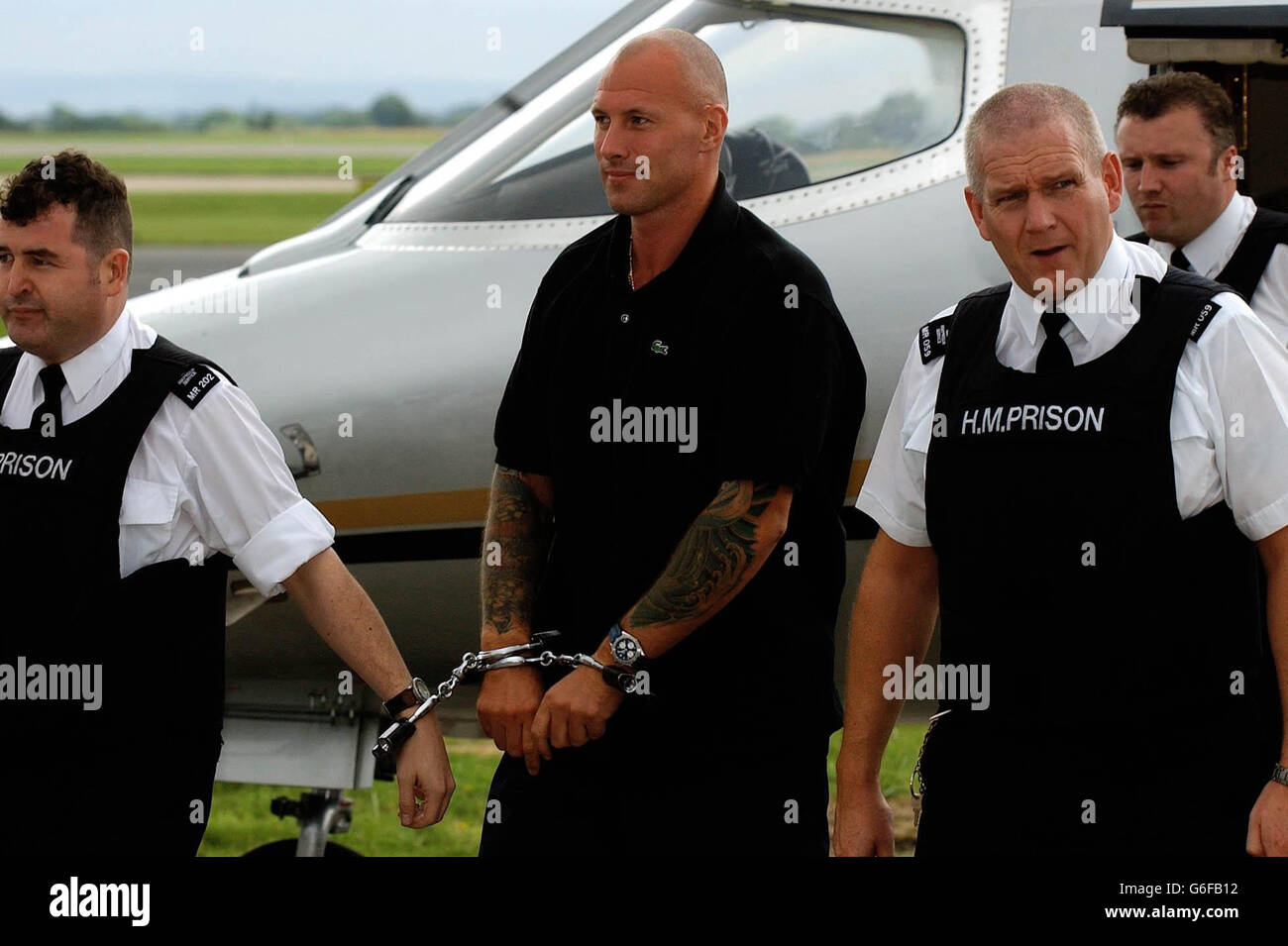 John Barber is handcuffed to prison warders as he is brought from an aircraft at Manchester Airport,following his extradition after being captured by police in the picturesque village of Sant Pol de Mar, north of Barcelona, Spain, in August last year. Barber, 36, jumped bail halfway through his crown court case in which he was accused of masterminding a major drugs cartel which dealt in heroin and crack cocaine worth millions of pounds. He was convicted in his absence at Liverpool Crown Court in January 2002 and sentenced to 22 years for conspiracy to supply Class A drugs. Stock Photo