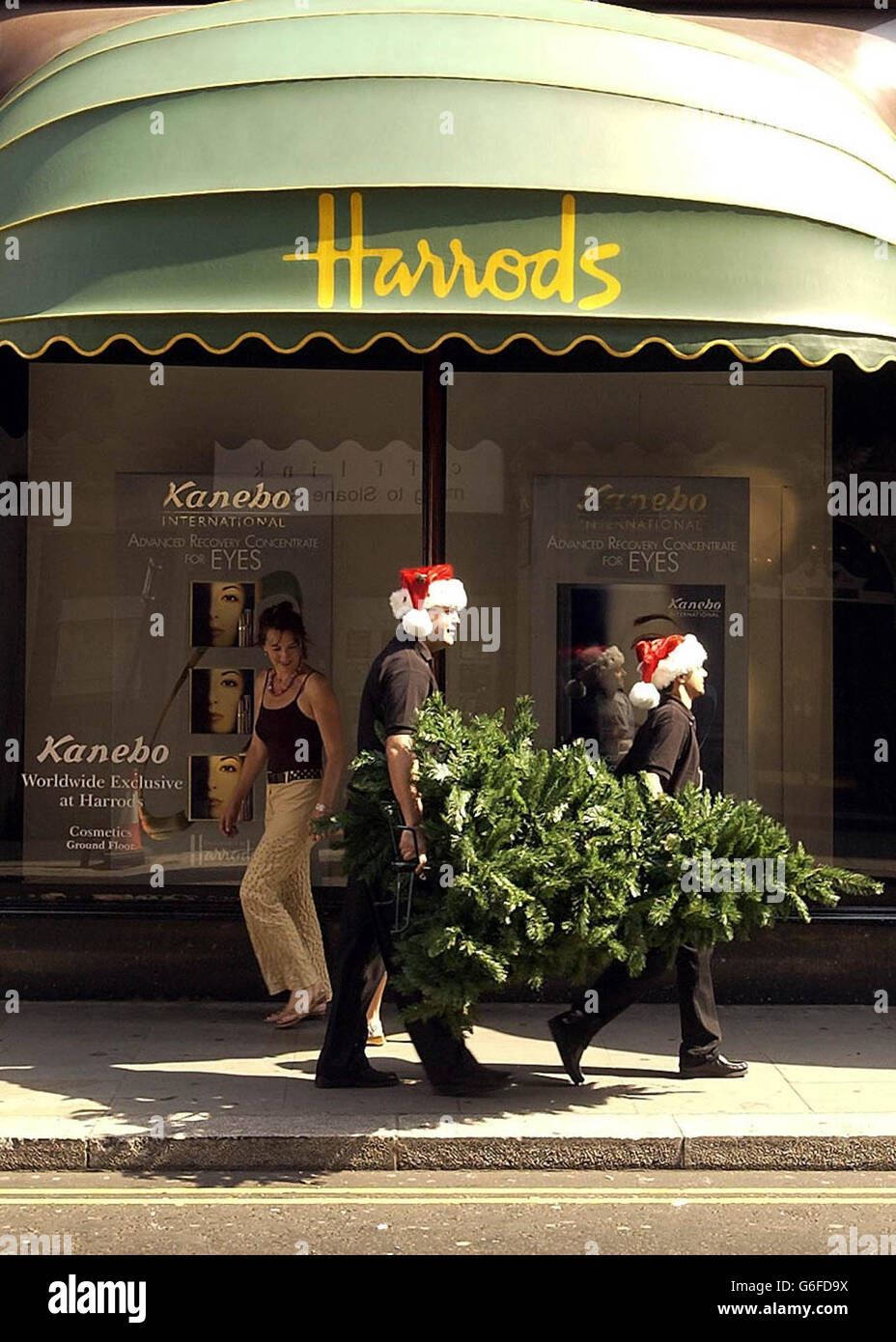 Two Harrod's employees carry a Christmas tree past the entrance of the