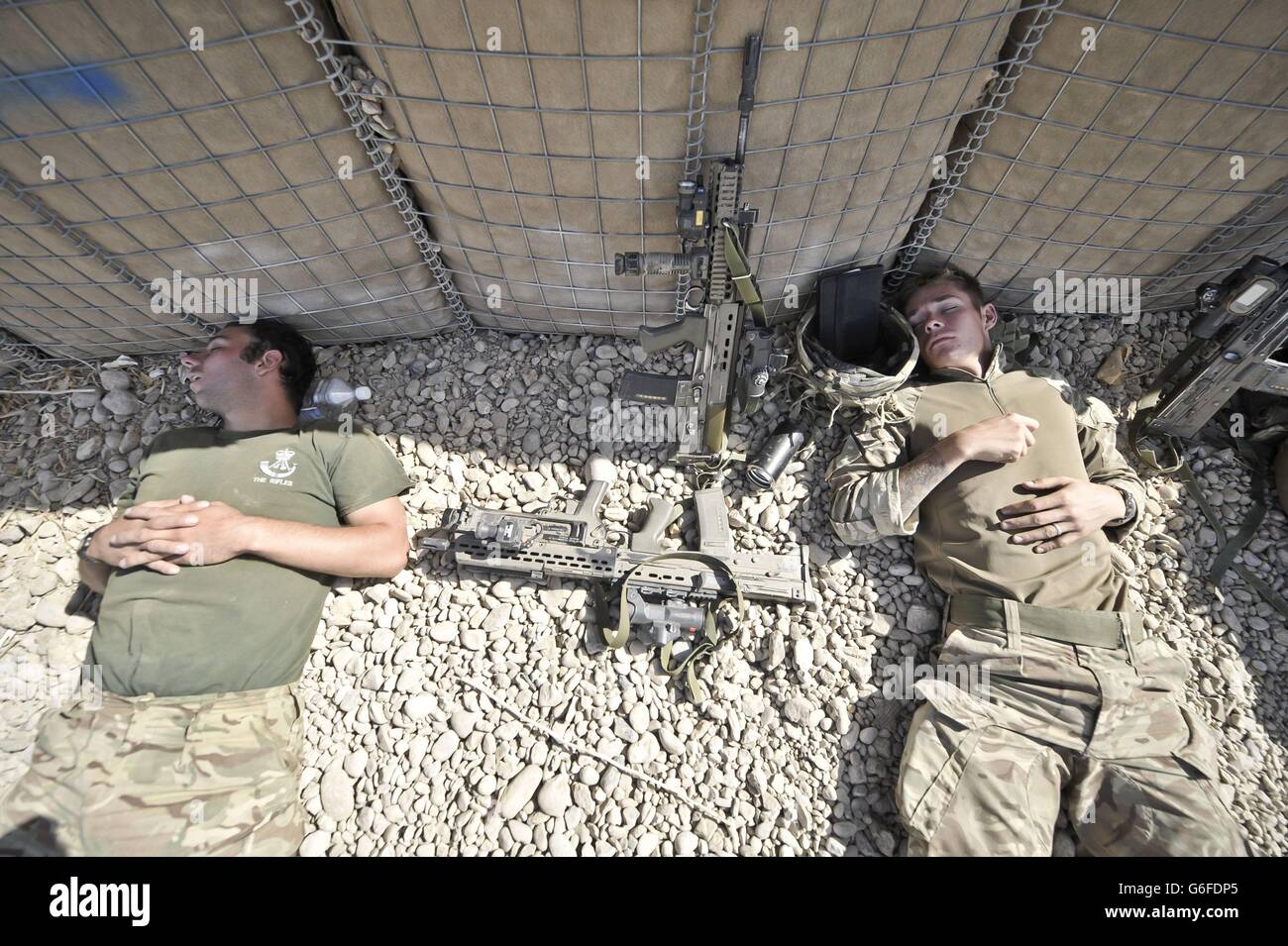 British Soldiers sleep next to a HESCO wall in a Patrol Base in the Helmand Province of Afghanistan, where the penultimate deployment, Operation Herrick 19 is underway. Stock Photo