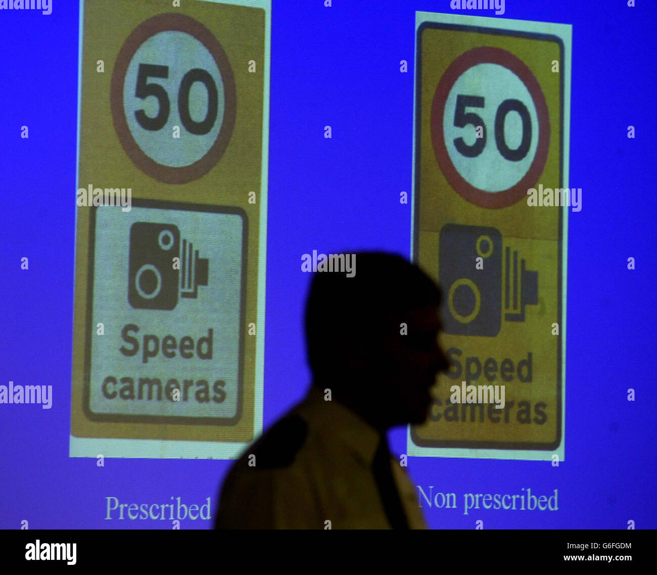 Acting Assistant Chief Constable of Cleveland Police John Burke (silhouetted) at a news conference in Middlesbrough, with the two different speed camera signs involved in the row over 'non-prescribed' or incorrect speed camera signs in his force area. Mr Burke said he was 'embarrassed' by the way two officers from a neighbouring force successfully beat speeding charges last week after claiming the thin black border around the joint 50mph speed limit and speed camera warning sign had not been prescribed by the Department of Transport. Stock Photo