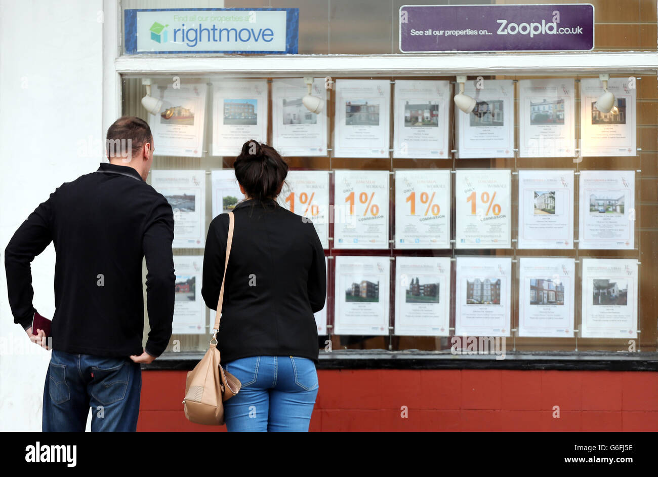 Couple look houses sale in estate window in allerton hires stock