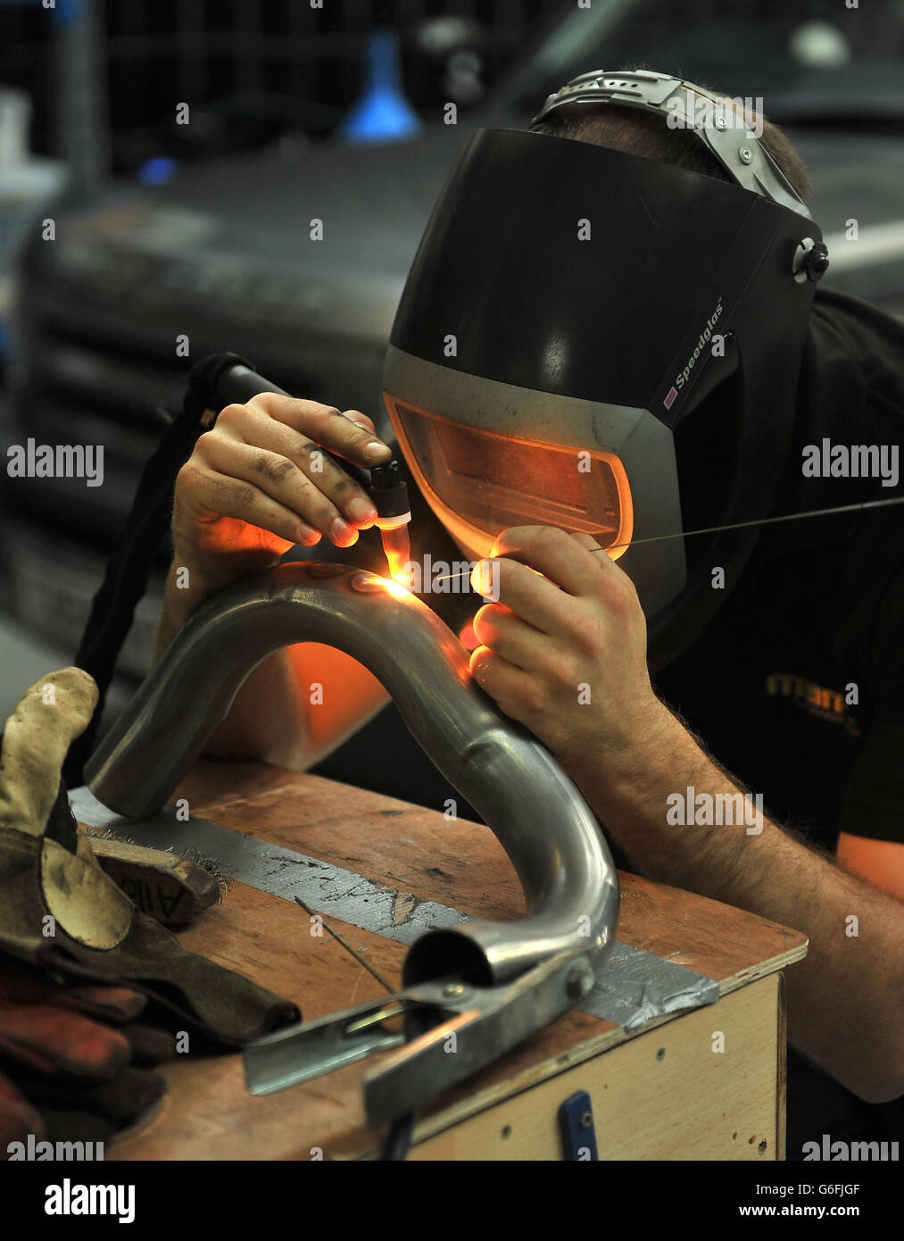 A mechanic works on an exhaust system using Gas Tungsten Arc Welding