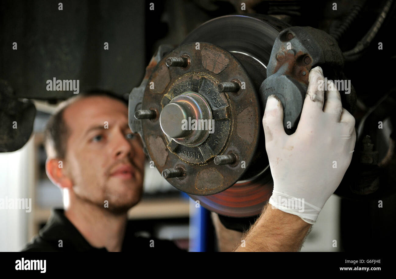 A mechanic inspects the brakes on a Bentley car in his workshop Stock Photo
