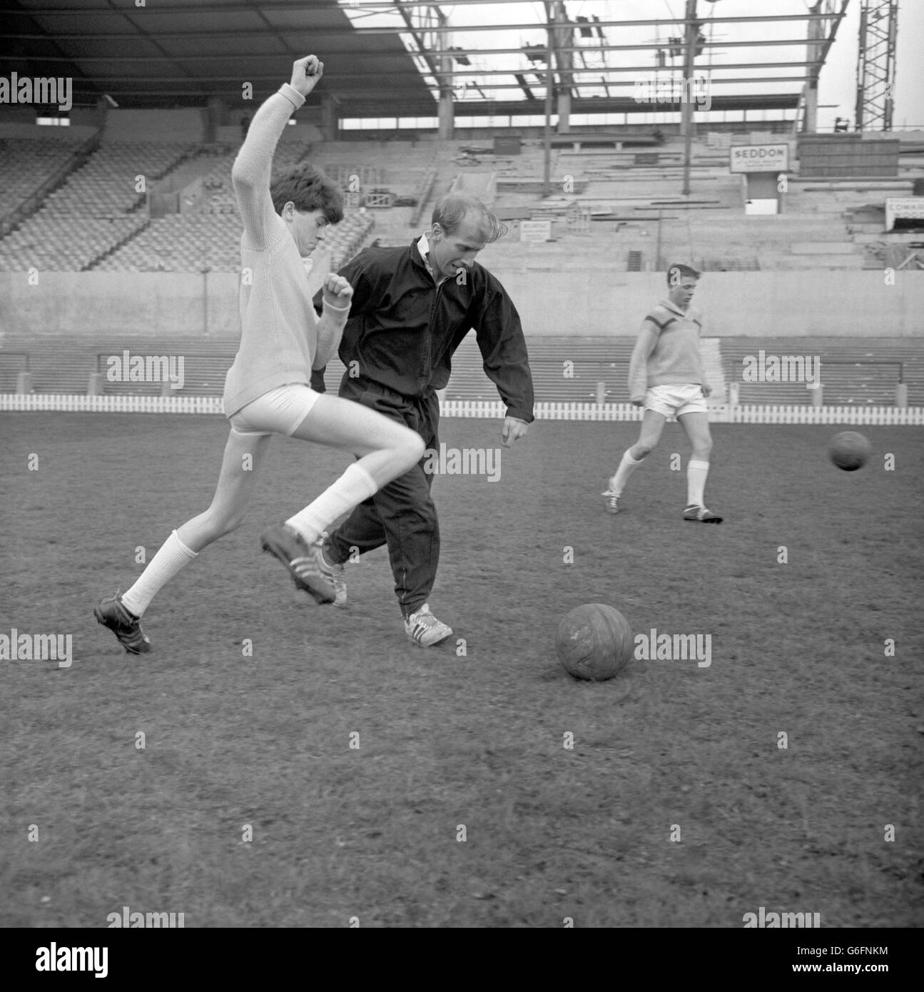 Glenn Slowther, of Bradford, challenges Manchester United's Bobby Charlton for the ball at Old Trafford. He is one of the schoolchildren from across the UK helping to make a film entitled 'Cup Fever' for the Children's Film Foundation. Manchester United are featured in the film. Stock Photo
