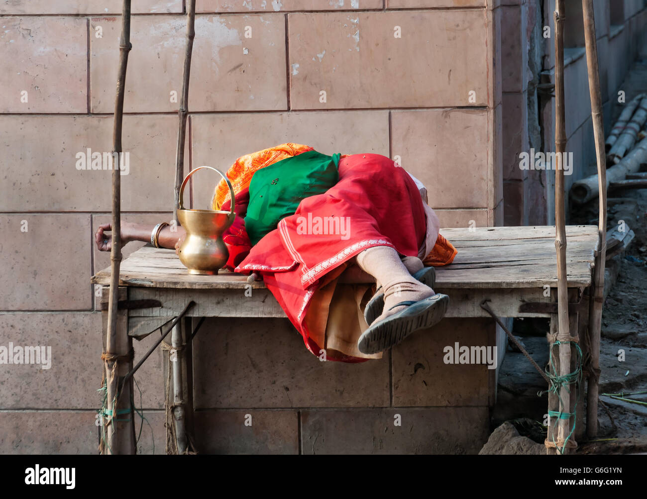 Indian woman sleeping on wooden table in the street. The major tradition followed in the area Stock Photo