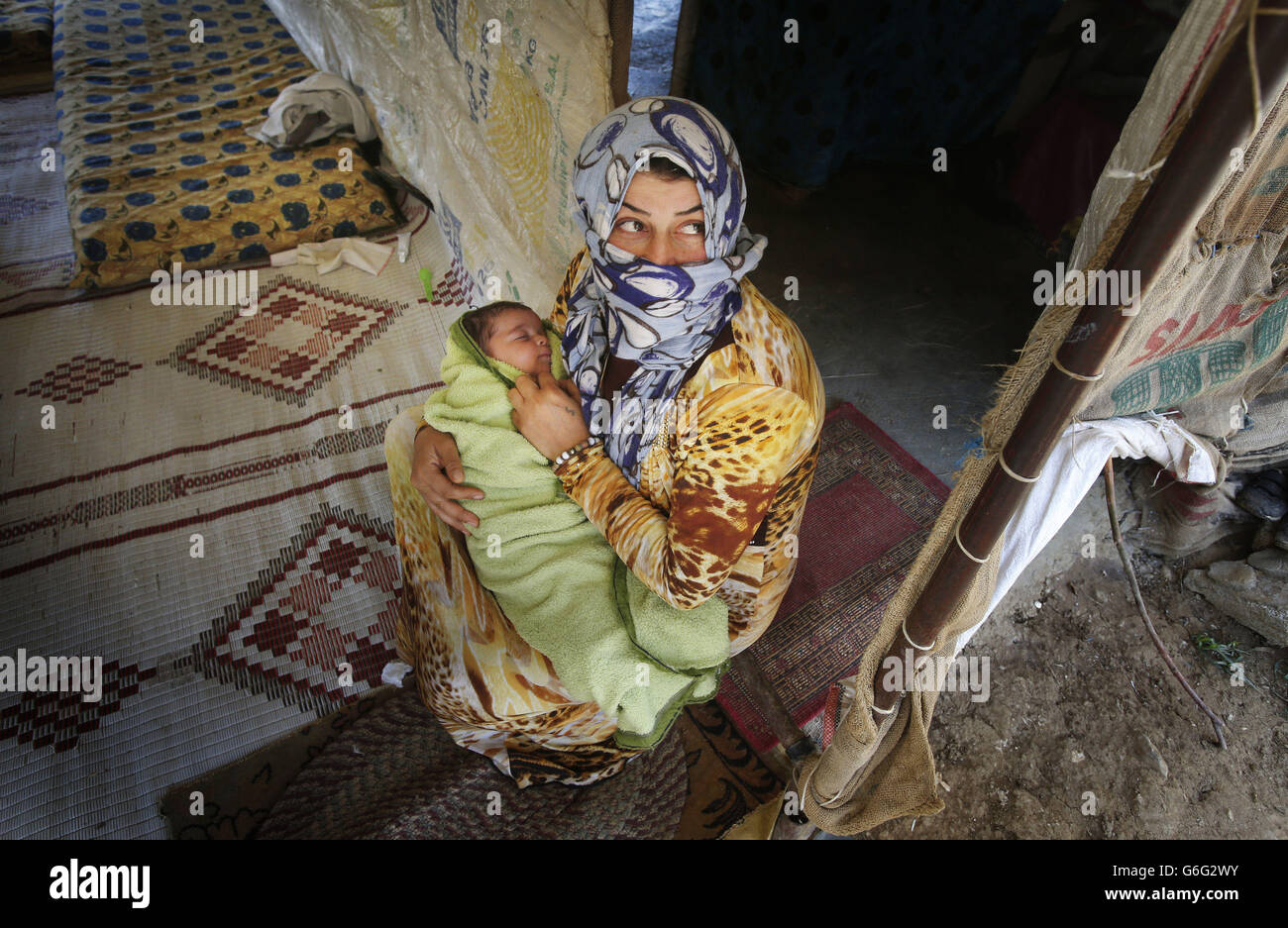 Syrian refugee Shaha Ibrahim and her two month-old daughter Bayane, who fled their home in Syria after 18 days of fighting that killed two of Shaha's cousins, in the makeshift settlement of Qab Elias in the Bekaa Valley, Lebanon. Stock Photo