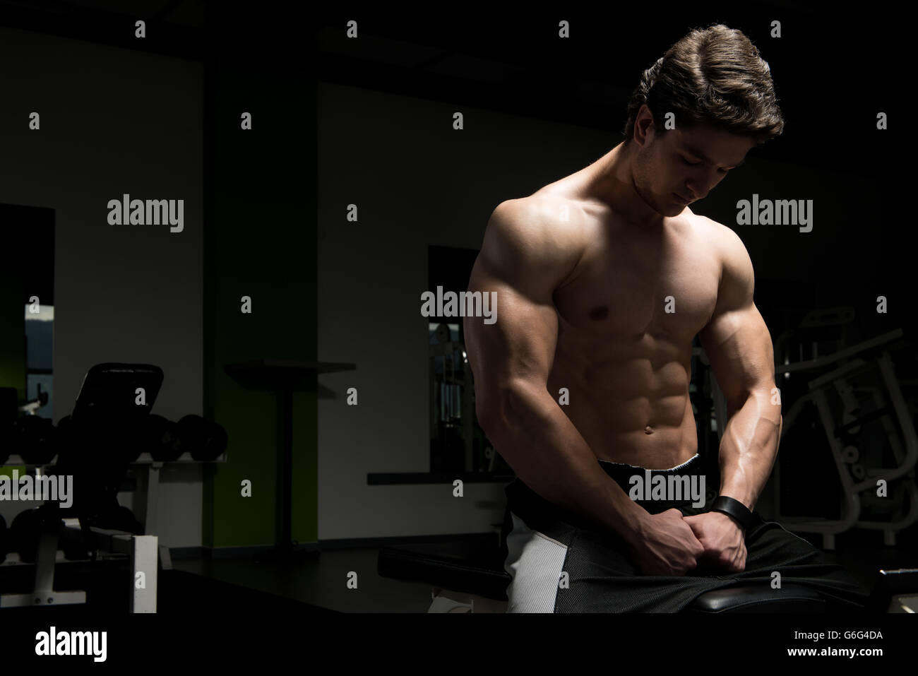 Good Looking And Attractive Young Man With Muscular Body Sitting On Bench And Relaxing In Gym Stock Photo