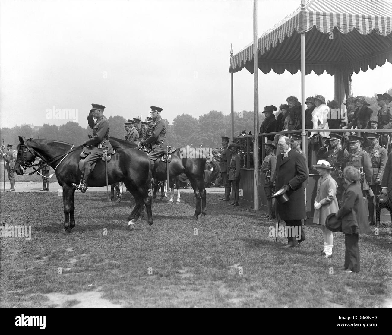 The King taking the salute as the troops march past. In the stand are seen the Queen, Princess Mary, Princess Arthur of Connaught, Princess Christian, Princess Royal, and Princess Beatrice. In front of the stand in Winston Churchill. Beside the King are the Duke of Connaught, Prince Albert, Prince Henry, Prince Arthur of Connaught and the Earl of Athlone. Stock Photo
