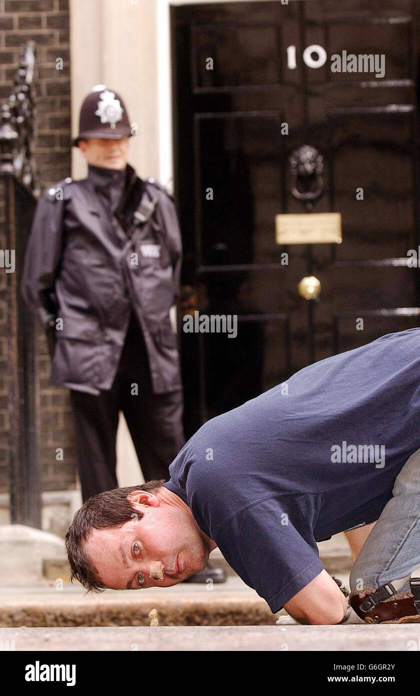 Mark McGowan, a 37-year-old artist from Peckham, south east London, arrives outside no.10 Downing Street. A man protesting against student debt completed the bizarre stunt today of rolling a monkey nut seven miles to Downing Street using only his nose. Crawling on his hands and knees, Mr McGowan nudged the nut over a kerb and up the steps to the famous black door of Number 10. He began his journey at Goldsmiths College in south east London on September 1, and has covered around three-quarters of a mile per day, working in eight-hour bursts. Mr McGowan handed the nut over to Number 10, along Stock Photo