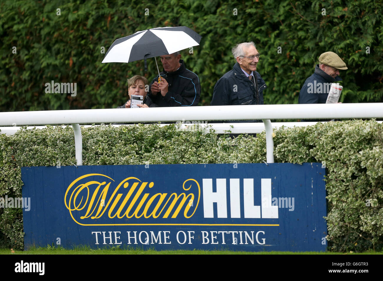 Horse Racing - William Hill Jump Sunday - Kempton Park Racecourse. Punters sheltering from the rain beside the parade ring at Kempton Park Racecourse Stock Photo