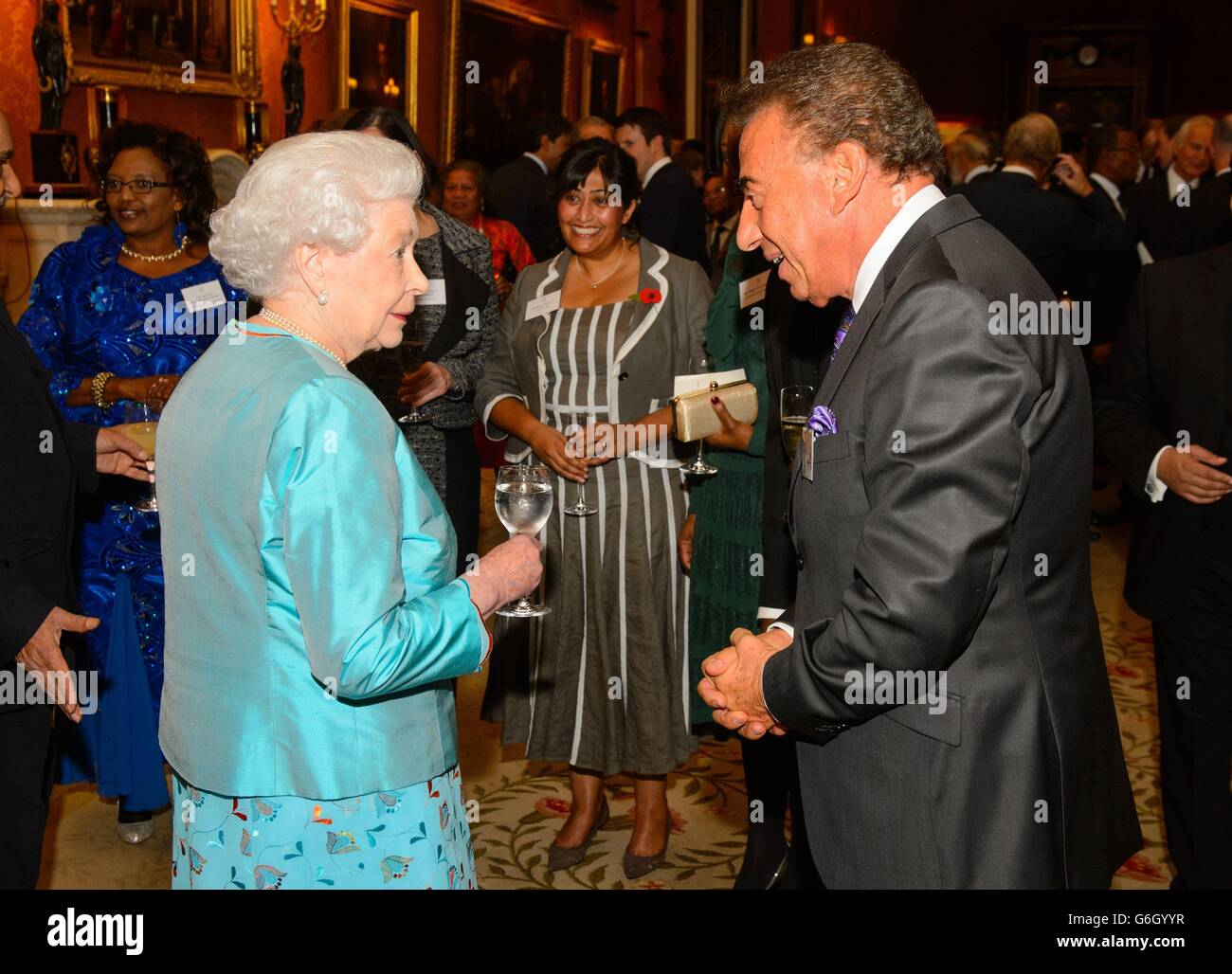 Queen Elizabeth II speaks with Cyril Dennis of Haven House Children's Hospice at a reception for Commonwealth nations representatives, at Buckingham Palace, in central London. Stock Photo
