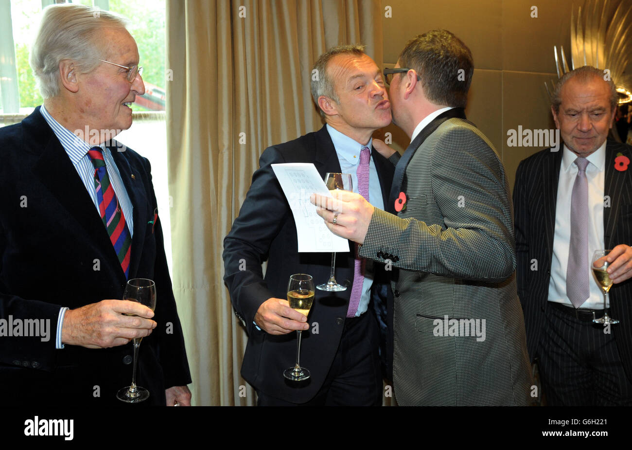 Guest of honour Graham Norton greets Alan Carr as Nicholas Parsons (left) and Lord Alan Sugar (right) look on during a tribute lunch hosted by The Lady Taverners at the Dorchester Hotel, London. Stock Photo