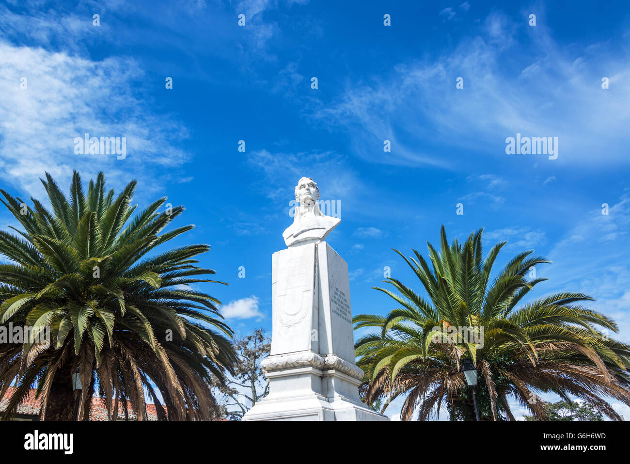 Bust of Antonio Narino in a public plaza in Villa de Leyva, Colombia with two palms trees and a beautiful blue sky visible Stock Photo