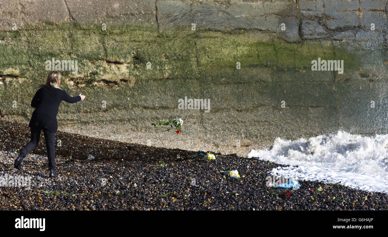 A woman throws flowers into the turbulent sea from West Beach in Newhaven, East Sussex where 14