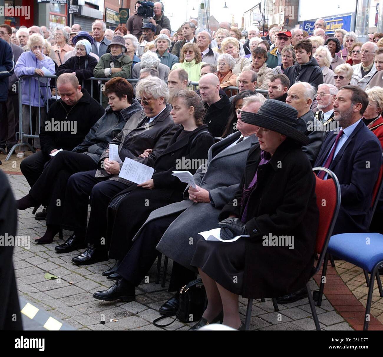 Mourners gather for a memorial service for his wife Marian in Arnold, Nottinghamshire. Mrs Bates was shot dead by armed raiders at her family jewellery store a week ago. Friends, fellow traders, civic dignitaries and residents joined Mrs Bates' husband Victor (front row, third left) and daughters Xanthe and Naomi today for the open air memorial service in Arnold Market Place, yards from Mrs Bates' shop. Stock Photo