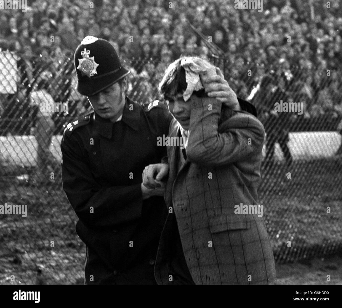 Police in Action at Chelsea. A Policeman escorts a young fan nursing an injured head at Stamford Bridge, where rioting spectators spilled over the barriers before the start of Chelsea's League Division Two promotion battle against London rivals Millwall. Stock Photo