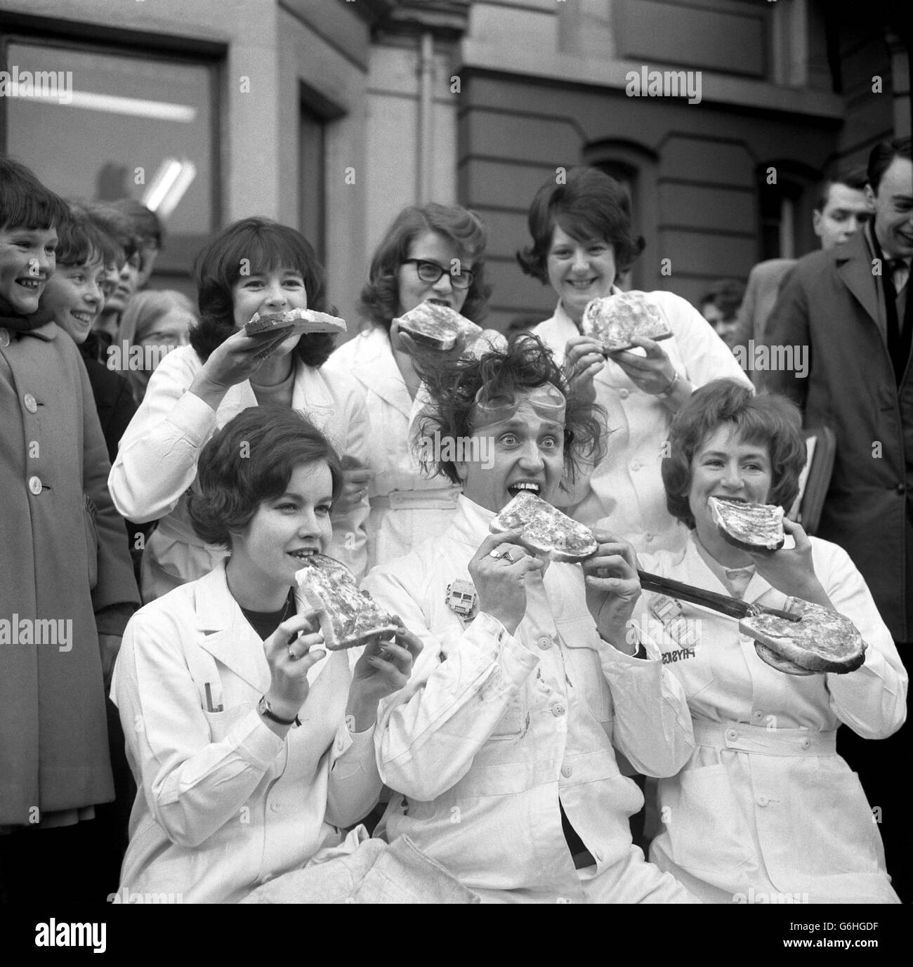 After being adopted as the official 'mascot' of the Nuclear Physics Laboratory at Manchester University, unruly-haired comedian Ken Dodd distributed jam-butties all round. Keeping company were Sandra Paton (right) and Maureen Richardson (left) and other technicians at the Laboratory. Stock Photo