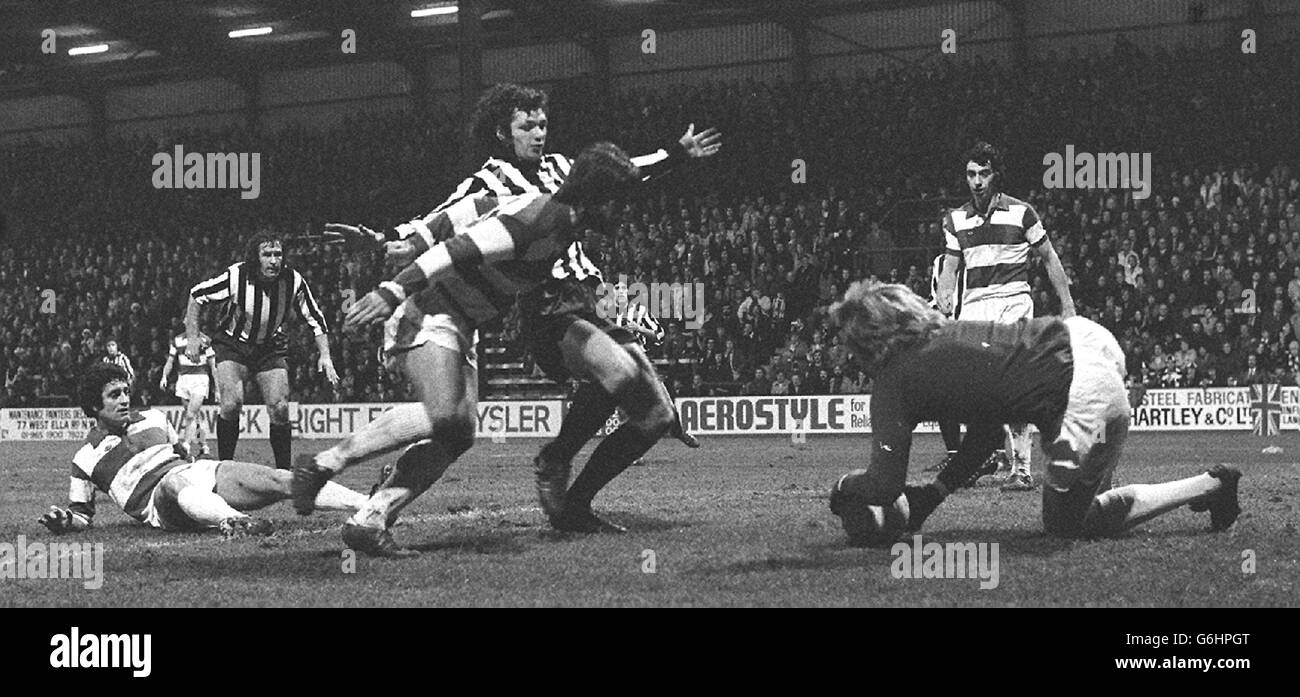 Attack by Notts County (stripes) snaps to a halt as Queen's Park Rangers' goalkeeper Phil Parkes dives on the ball in the fourth round FA Cup tie at Loftus Road, Shepherd's Bush. Grounded Frank McLintock, Rangers' No.5, watches on the left. QPR won 3-0. Stock Photo