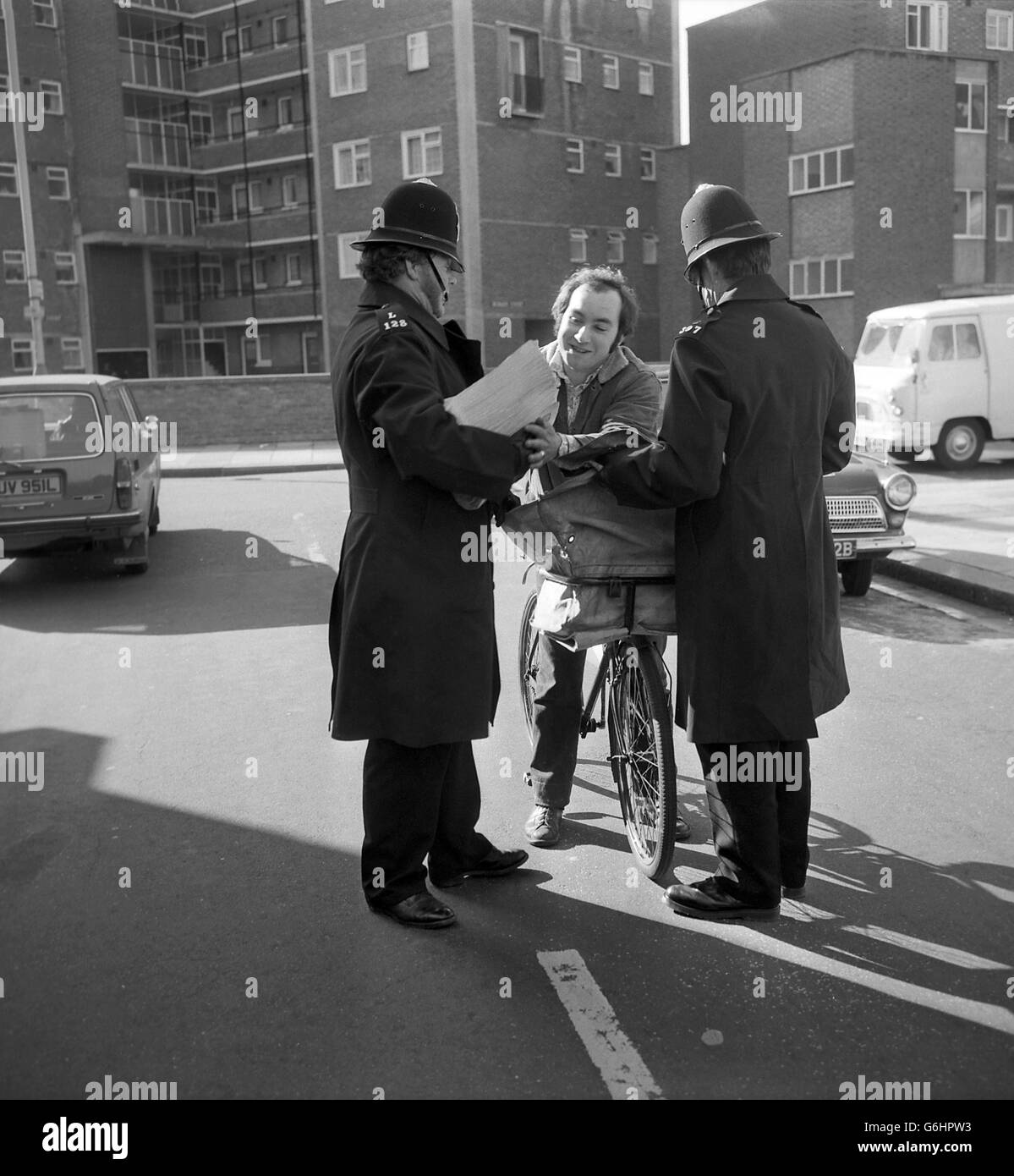 Police search a passing newspaper delivery man's bag as part of the security precautions at Lambeth Magistrates' Court, where seven men and three girls accused of plotting explosions in London last month were again remanded in custody for a week. Stock Photo