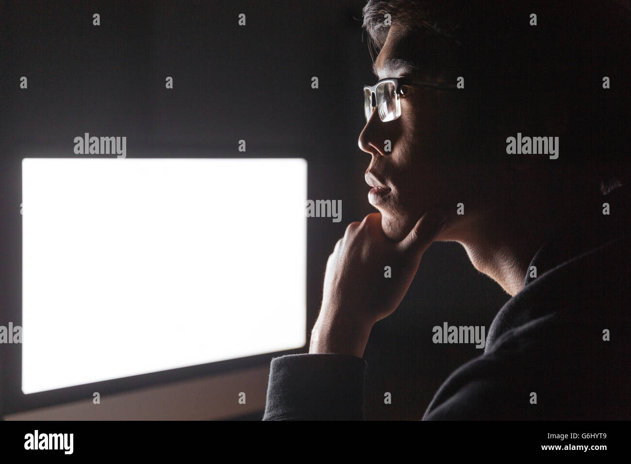 Computer Screen Thinking Pensive young man thinking and using blank screen computer in dark room ...
