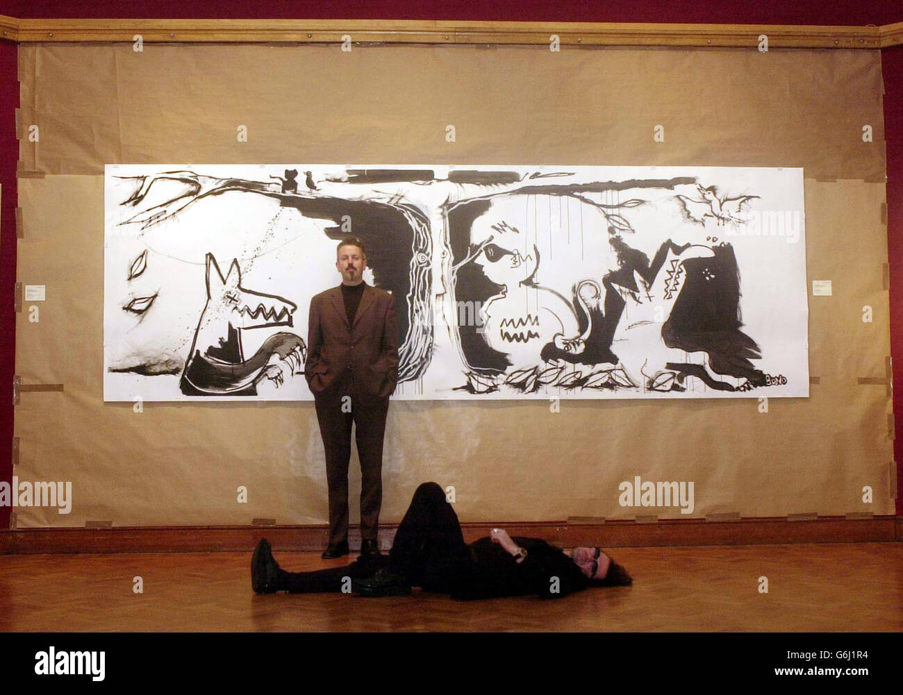 Musicians Gavin Friday (lying down) and Maurice Seezer stand before U2 singer Bono's 'Peter and the Wolf IV' illustration inside Christie's in Mayfair, London. Fifteen original illustrations created by Bono will be sold at a special gala auction in New York on November 21 to coincide with the publication of Peter and the Wolf by Bloomsbury Publishing on October 6. The take on Prokofiev's famous children's tale has been recorded by Friday and Seezer and is presented with a 64-page cloth-bound book illustrated by Bono. Stock Photo