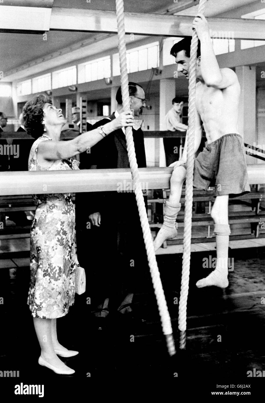 Queen Frederika of Greece smiles encouragingly at David Bonnett as he climbs a rope in the gymnasium during her visit to the Lord Mayor Treloar College for Disabled Boys at Upper Froyle, near Alton, Hampshire. She spent more than an hour visiting the classrooms and workshops. With her husband, Queen Frederika is on a State visit to Britain. Stock Photo