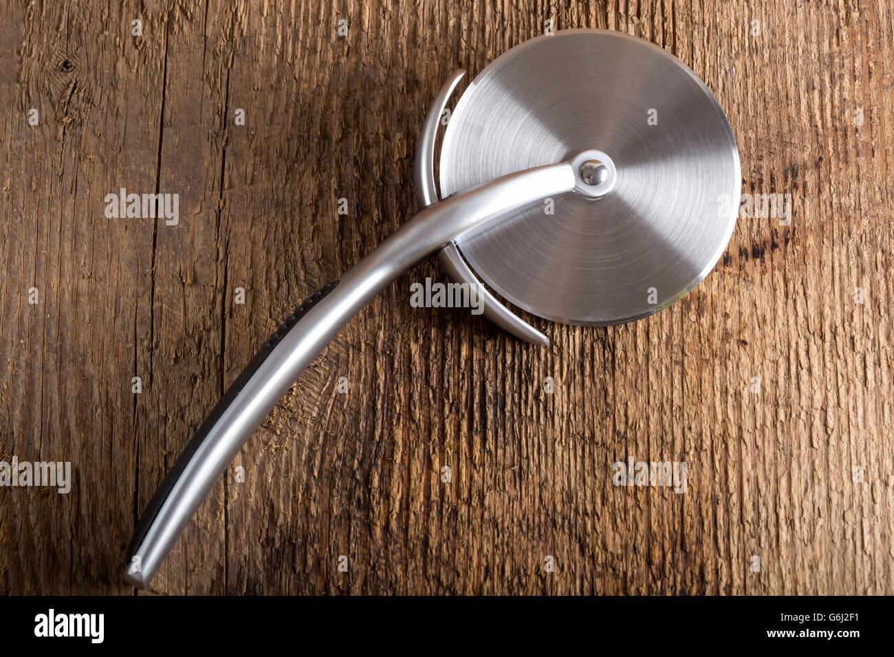 Circular Pizza Cutter on wooden rustic background Stock Photo