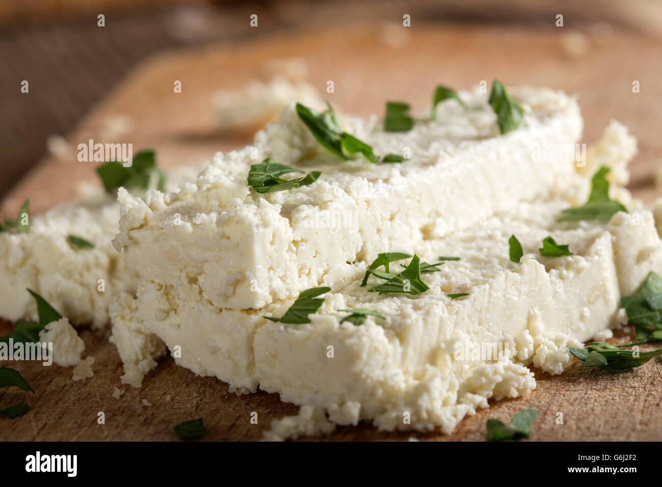 Fresh cheese slices on a wooden background with parsley Stock Photo