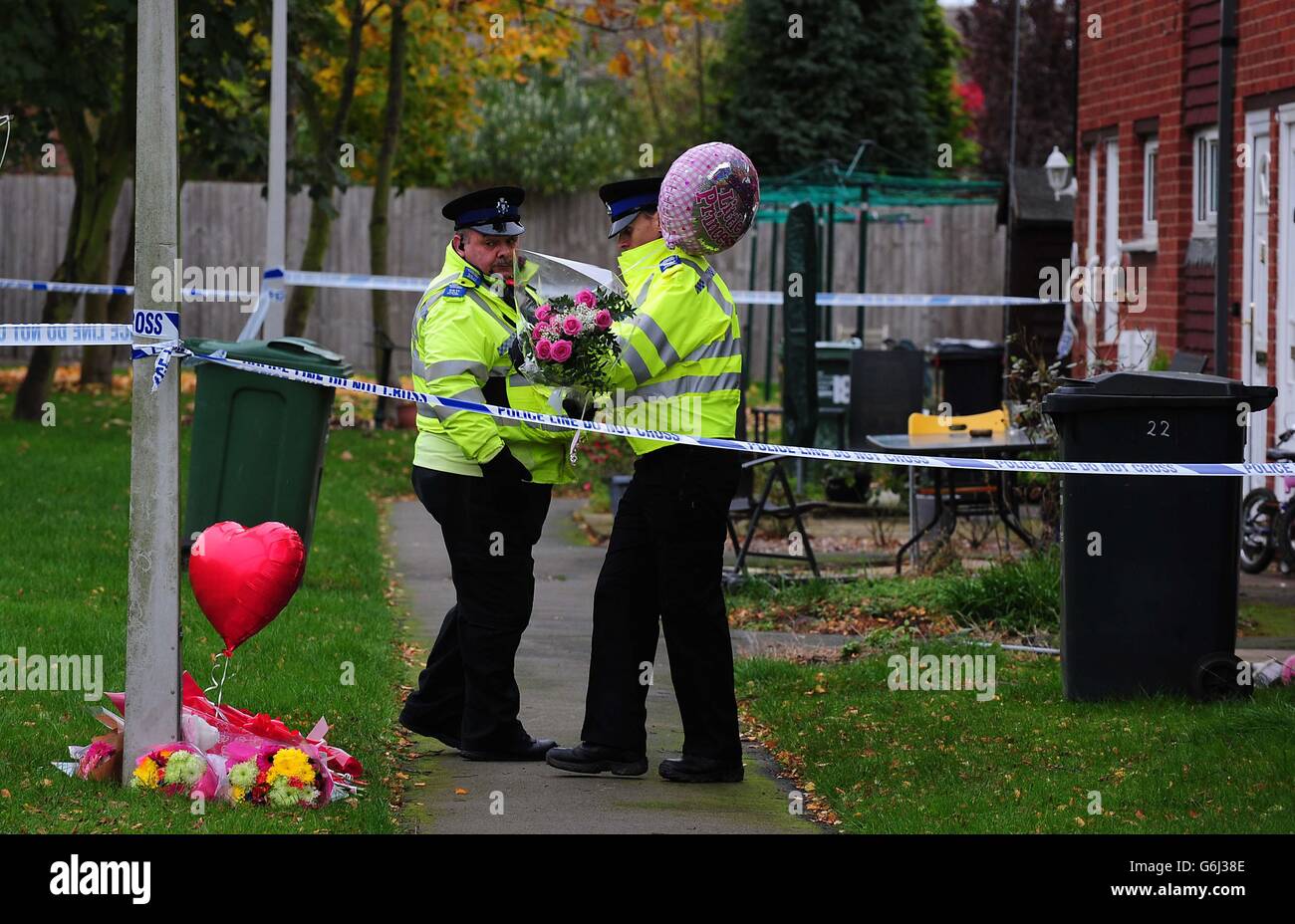 Police carry floral tributes outside the home in Rowena Court in Mountsorrel, Leicestershire where Lexi Branson, four, died after being bitten by a dog. Stock Photo