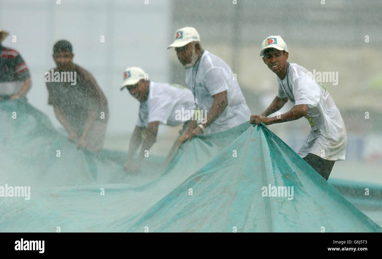 Ground staff at the Bangabandhu Stadium in Dhaka battle against torrential rain, after play in the inaugural Test between England and Bangladesh was halted after less than 20 minutes. Bangladesh had faced only four overs after winning the toss and deciding to bat and had reached one without loss when the storms broke over the ground and sent the players scurrying for the dressing rooms. Stock Photo